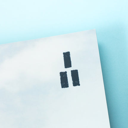 The top right corner of a magazine is visible featuring a bright cloudy sky and the Trails Magazine logo, three parallel dark blue rectangles stacked into a triangle making a trail market blaze.